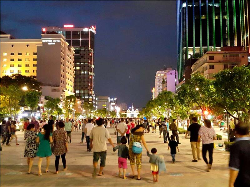 사람들은 호치민시에서 밤 시간에 nguyen 후에 도보 거리를 따라 걷는 것을 즐깁니다.