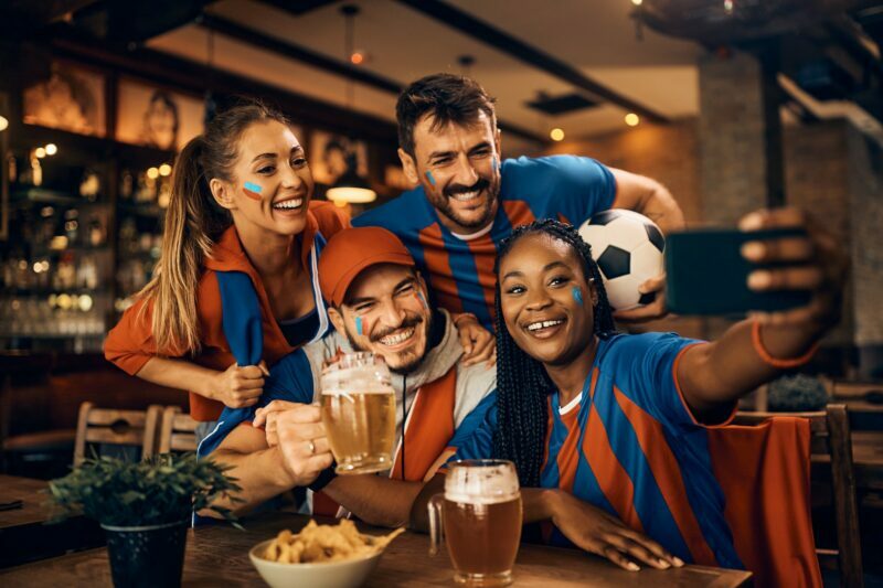 Group of happy soccer fans having fun while taking selfie during world championship in a bar.