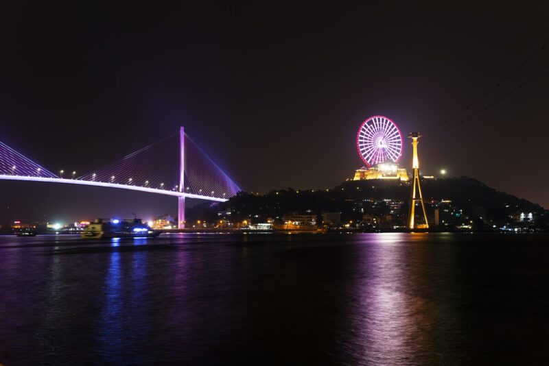 Vietnam at night is showing neon lights on a bridge and ferris wheel