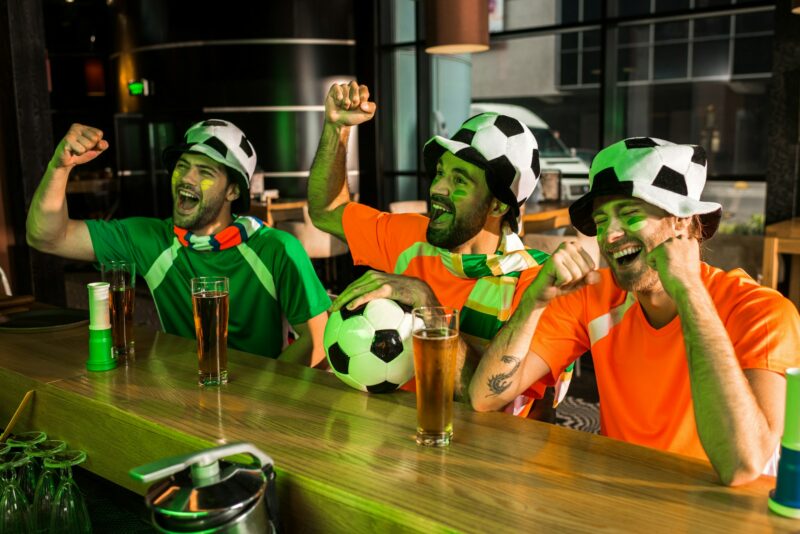 Peminat bola sepak bersorak dan menjerit di bar menonton liga juara